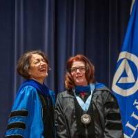Provost Mili laughs next to woman on stage